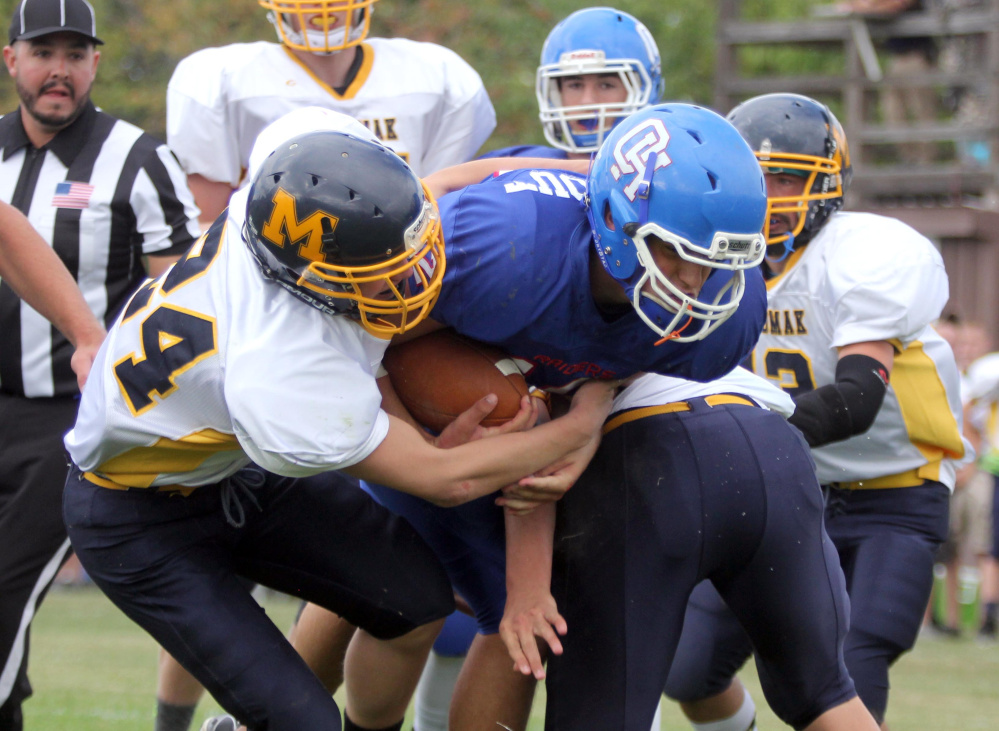 Oak Hill quarterback Matthew Strout carries the ball and Medomak's Drew Severson into the en dzone for a touchdown during the first half of a Campbell Conference Class D game Saturday afternoon in Wales.