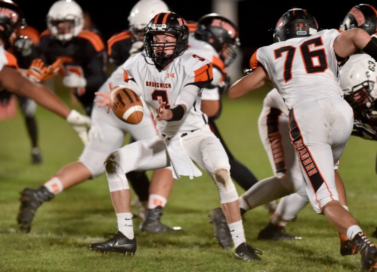 Brunswick quarterback Christian Jensen pitches the ball to Hunter Garrett during a Pine Tree Conference Class B game Friday night in Skowhegan.