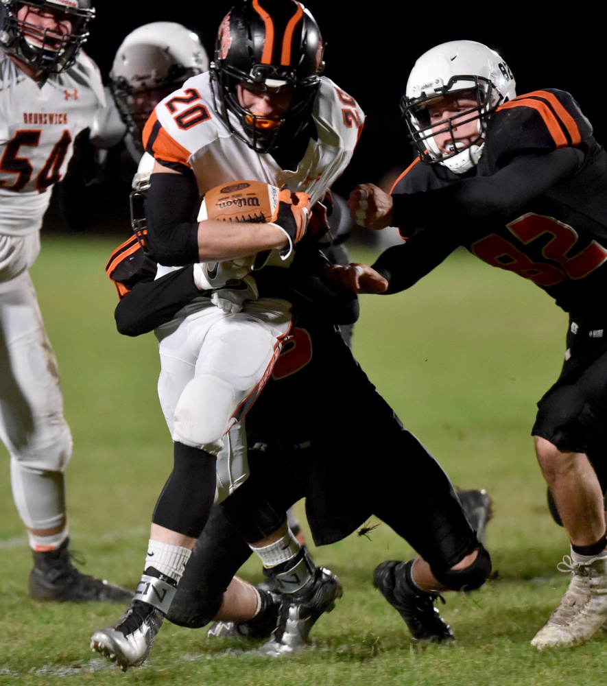 Skowhegan's Kobe Houghton (25) and Garrett McSweeney, right, try to tackle Brunswick running back Hunter Garrett during a Pine Tree Conference Class B game Friday night in Skowhegan.