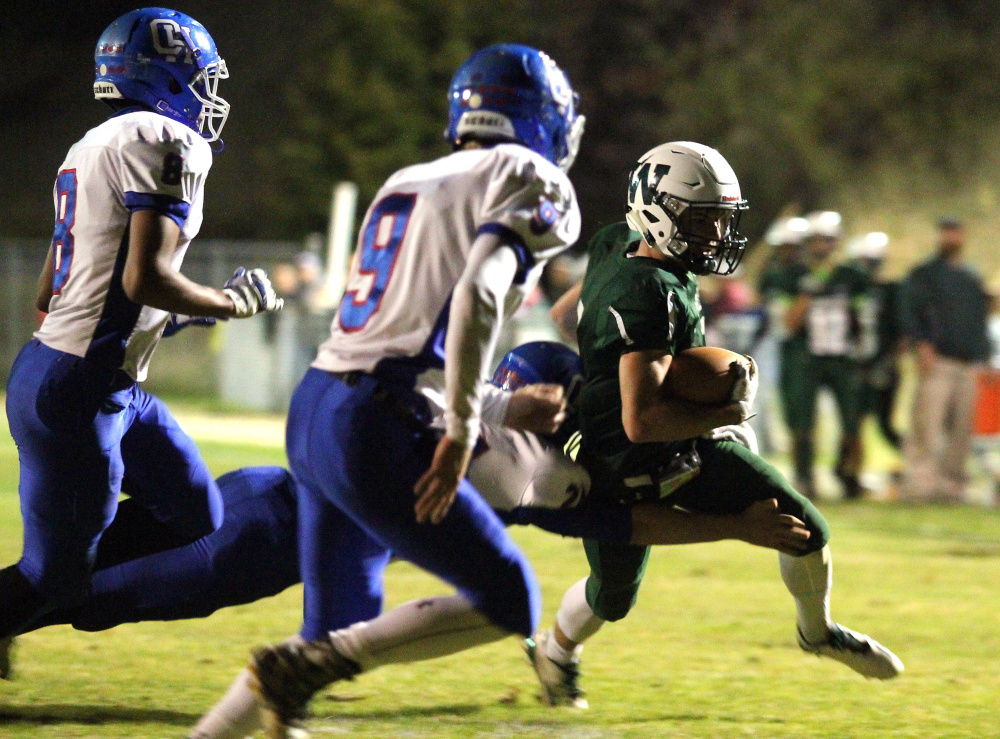 Winthrop/Monmouth's Nate Scott tries to find the end zone while being tackled by Oak Hill's Brian Thorpe during first-half action last Friday night in Winthrop. Also in pursuit are Oak Hill's Darryn Bailey (8) and Danny Buteau (9).