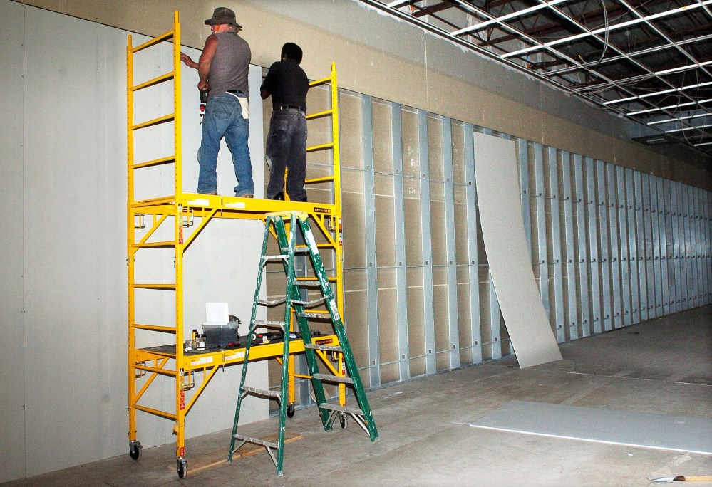 Roger Clinton, left, and Dwayne Oudkerk-Pickett install large pieces of wallboard on walls Wednesday for the veterans museum under construction at the Skowhegan Village Plaza.