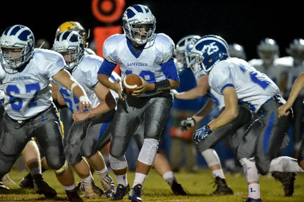 Lawrence quarterback Braden Ballard drops back to hand the ball off to Riley Parlin against Mt. Blue last month in Farmington.