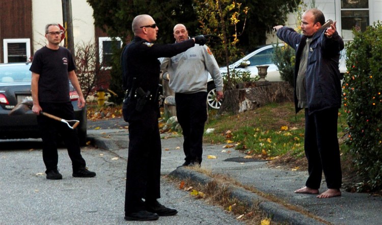 A Waterville police officer orders Daniel Groover, right, to hold up his hands up after confronting the man on Appleton Street in Waterville on Monday. Groover reportedly smashed a rear window in the Waterville Fire Department building and was followed by firefighter Al Nygren, left, with a shovel, and Capt. Rodney Alderman.