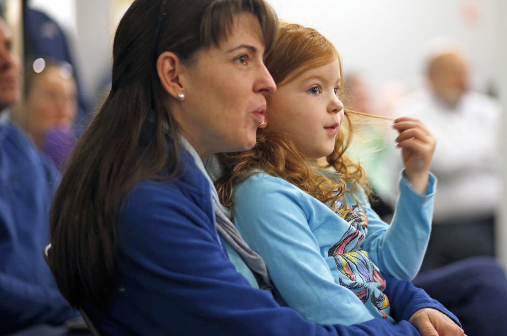 Devon Yates, 4, triwlrs her hair while she and her mom Sara Yates recite poetry along with illustrator Ashley Bryan during an appearance at Portland Public Library. 