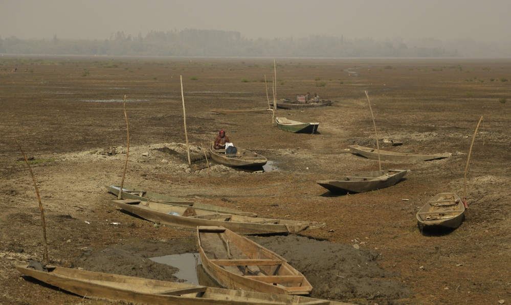 A Kashmiri woman sits inside a boat in a dried portion of Wular Lake in Indian-controlled Kashmir. India has realized that the vast, alpine lake would be worth more if it were pristine than exploited for resources. 