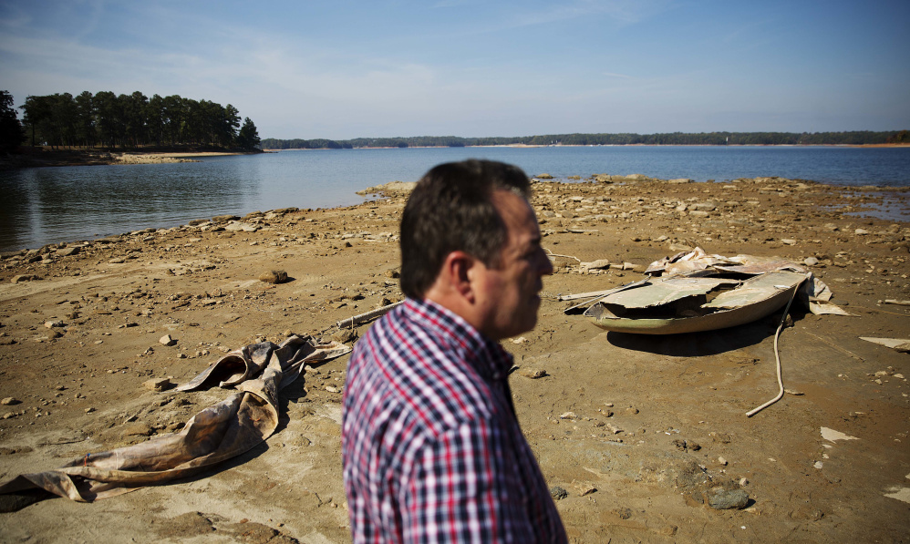 A sunken boat is exposed on Lake Lanier as the Army Corps of Engineers Natural Resources Manager Nick Baggett looks on in Flowery Branch, Ga. Southerners are beginning to realize that they'll need to conserve water for drinking.