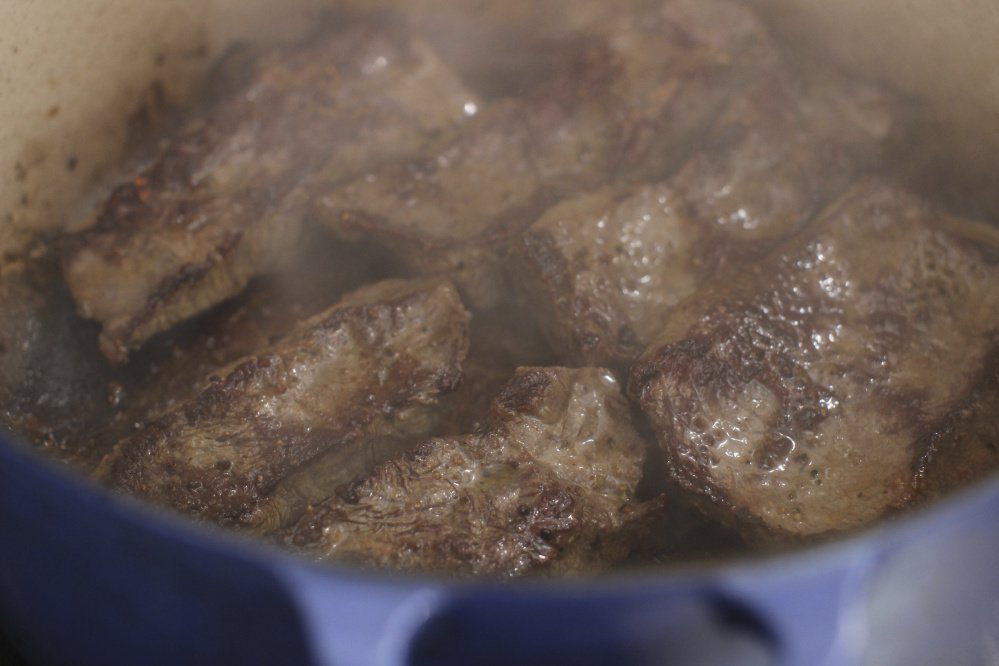 Short ribs being braised, a basic cooking technique that uses a slow, wet heat in a covered pot.