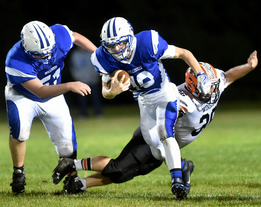 Madison quarterback Evan Bess evades Winslow defender Kenny Rickard during a Big Ten Conference game earlier this season in Madison. The Bulldogs and Black Raiders will meet in a BTC semifinal Friday night at Rudman Field in Madison.