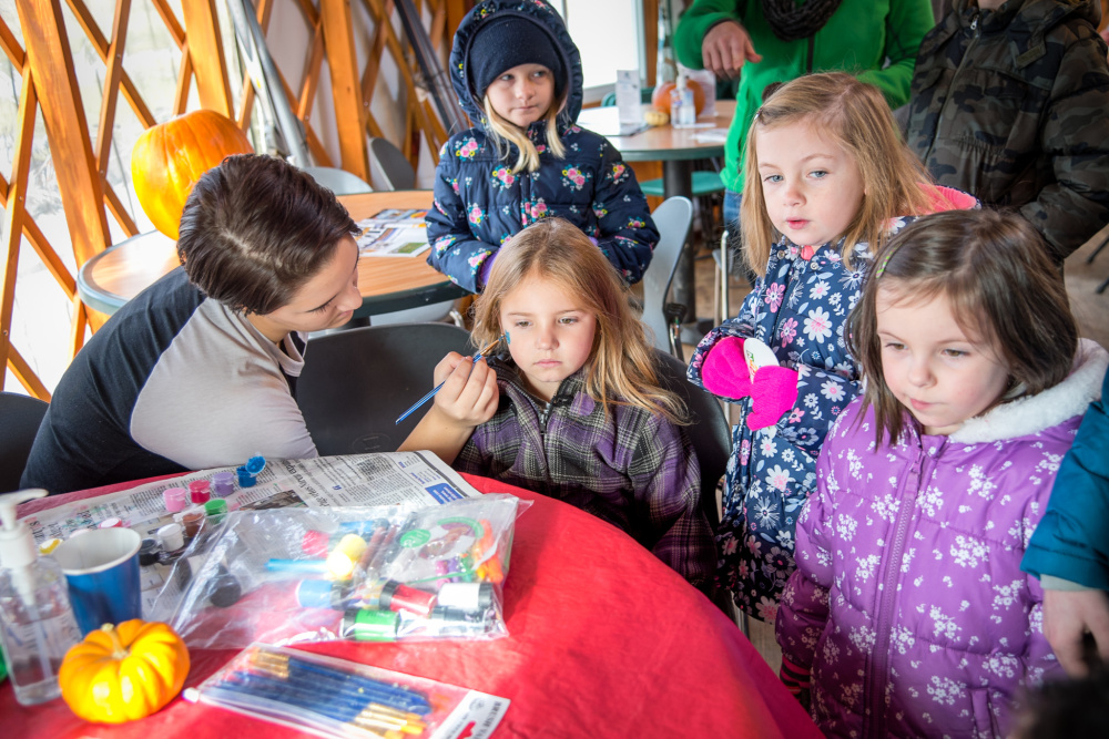 Brenna Rolfe gets a cat painted on her face Saturday by Fall Festival volunteer Cailynn Colby at the Quarry Road Trails recreation area in Waterville.