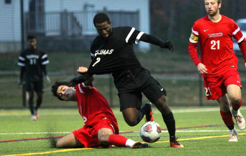 Thomas College's Tevin Reid gets dragged down by New England College's Sina Simali in the second half of the North Atlantic Conference championship in Waterville on Saturday night.