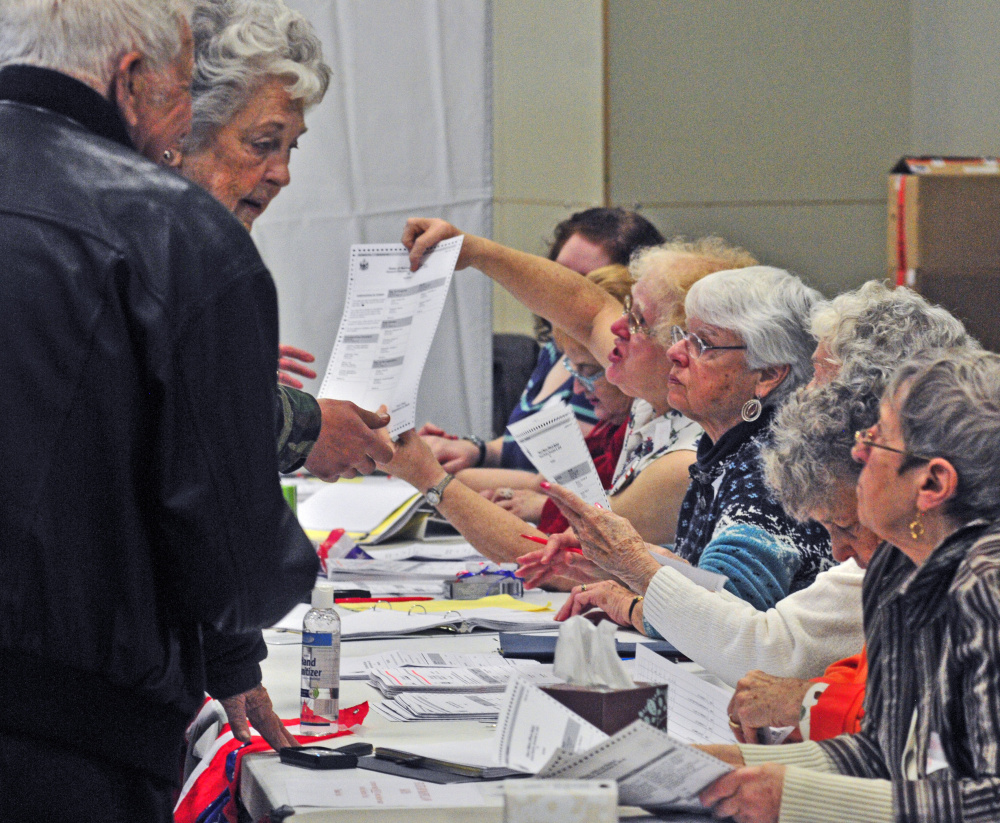 Voters get ballots from a table of election workers Tuesday at the Boys & Girls Club of Greater Gardiner, where Clerk Lisa Gilliam said there was a 70 percent turnout.