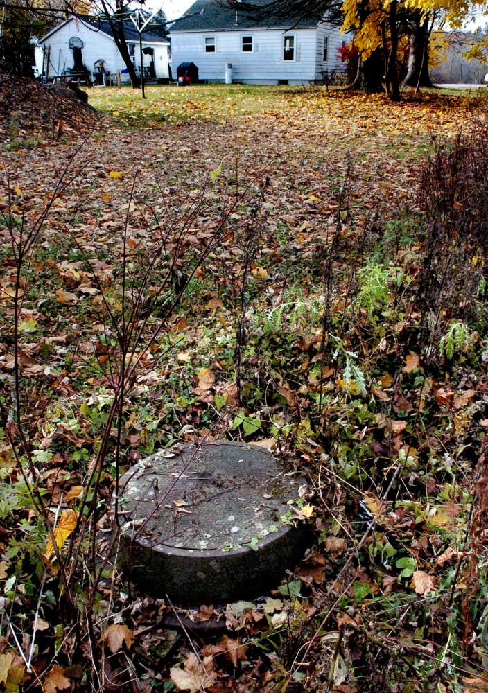 This manhole cover and water drain in a wooded area between Fairfield Street and the Oakland wastewater treatment facility in Oakland is in a low drainage spot and has areas below the rim that allow runoff water to enter the system. Officials hope to fix that and other sewer system issues this fall.