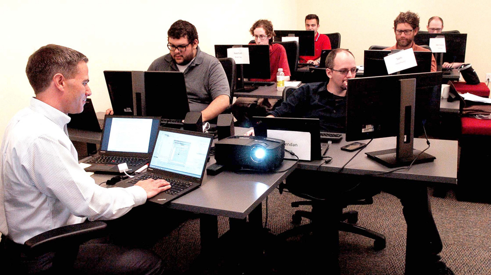 Collaborative Consulting trainer Tristan Lewis assists employees learning one of the systems at the Hathaway Creative Center in Waterville in August. Collaborative Consulting, a Massachusetts-based technology company, recently was purchased by CGI Group Inc.