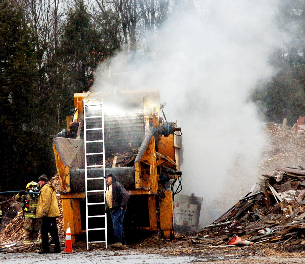 Firefighters from Oakland extinguish a burning grinder belt in a machine used to grind debris that was damaged by fire at the Oakland Transfer Station on Tuesday.