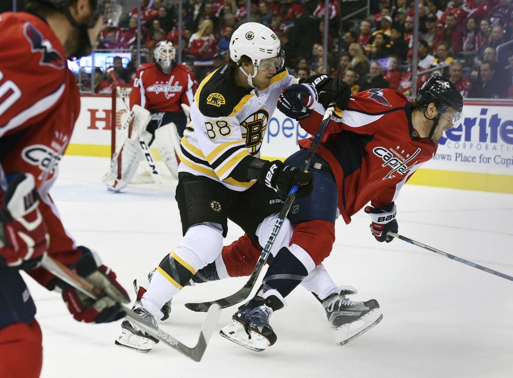 Boston's David Pastrnak trips Capitals defenseman John Carlson in the first period Wednesday night in Washington.