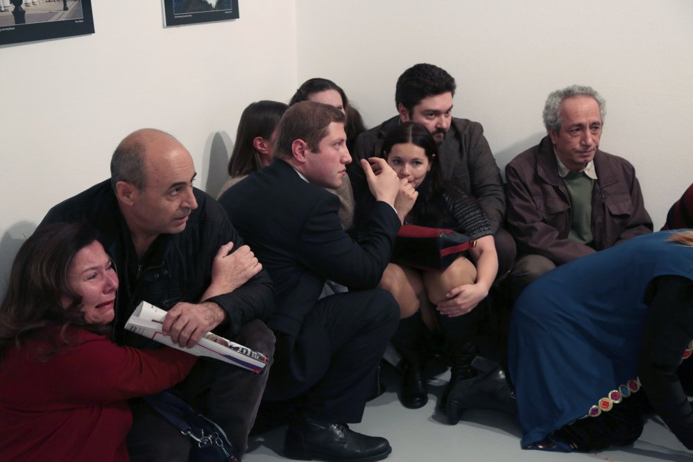 People crouch in a corner after Andrei Karlov, the Russian ambassador to Turkey, was shot at a photo gallery in Ankara, Turkey, on Monday. Turkey and Russia plan to work together to investigate the assassination.