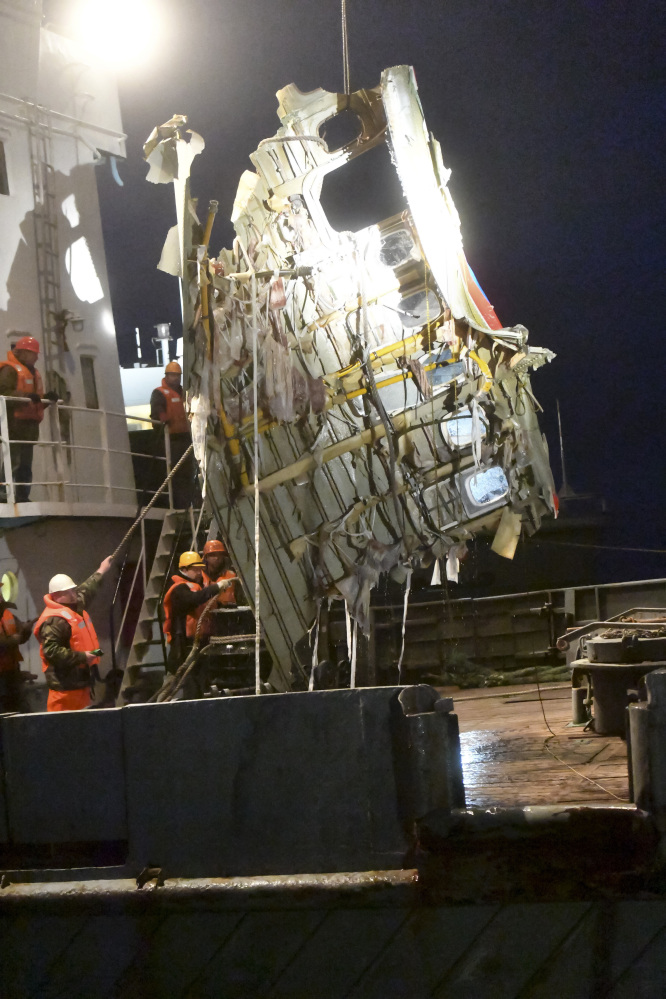 Russian Emergency Ministry employees lift a fragment of a plane outside Sochi, Russia. Rescue workers on Tuesday found a flight recorder from the Russian plane that crashed into the Black Sea over the weekend, the defense ministry said. All 84 passengers and eight crew members on the Russian military's Tu-154 plane are believed to have died.