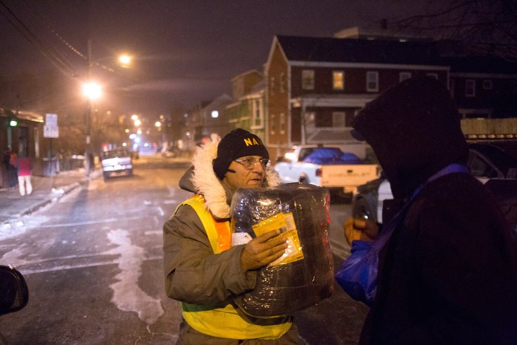 Roger Goodoak, executive director of the Maine Homeless Veterans Alliance, hands a sleeping bag to a homeless man named Wayne, who declined to give his last name and planned to sleep Thursday night in the doorway of a store that lets him seek shelter.