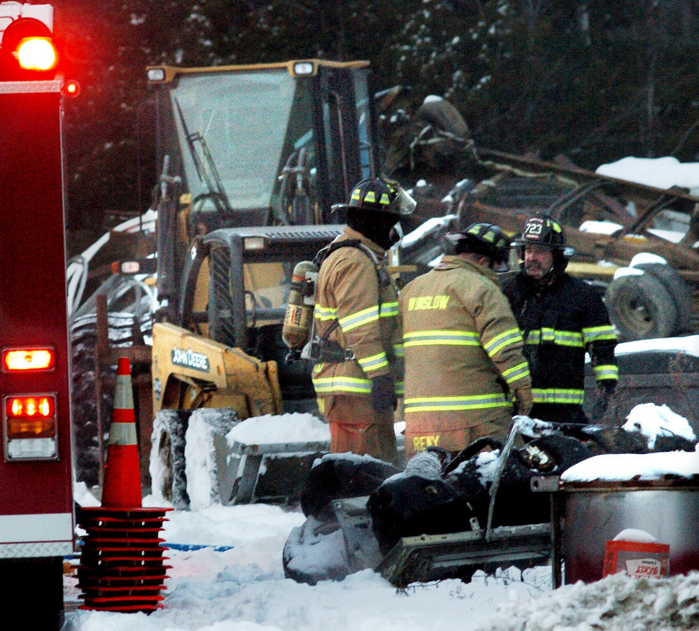 Winslow firefighters assemble to put out a fire at the MSR Recycling building on Tuesday. In the background is equipment that was reportedly used to haul snow to douse the fire.