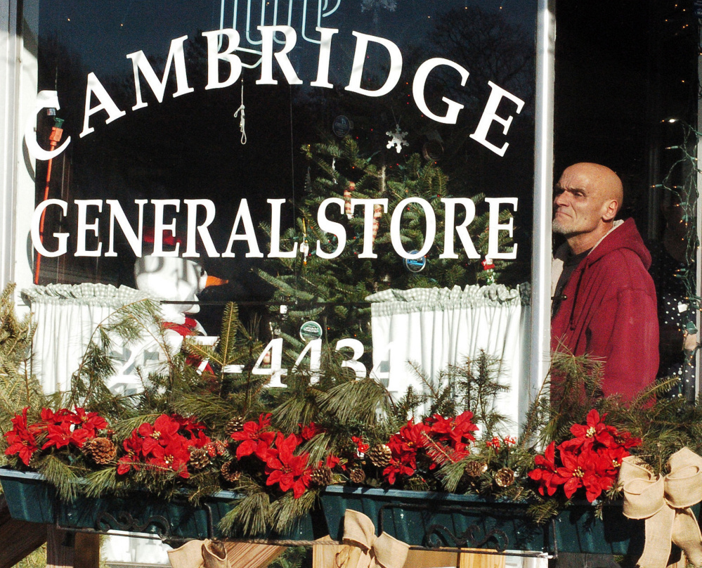 Greg Davis, who leased and operated Bunker's Garage in Cambridge, watches on Dec. 11 from inside the Cambridge General Store and Restaurant as fire destroys his business.