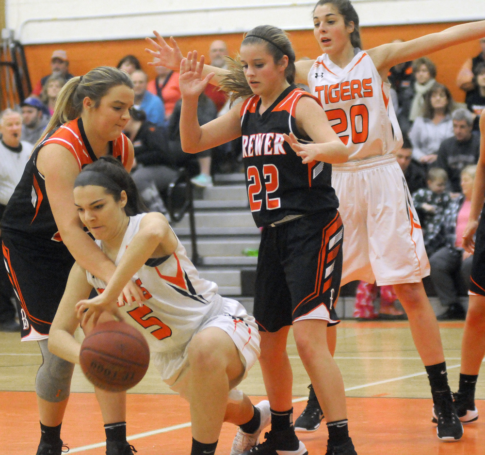 Gardiner's Anna Toman (5) breaks throug the defense of Brewer's Rebecca Gideon, left, and Cassidy Smith during a Class A North game Wednesday in Gardiner.