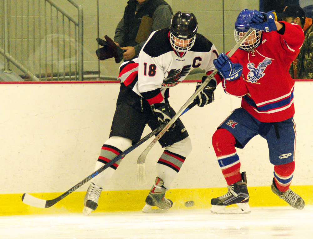 Maranacook/Winthrop's Matt Ingram, left, and Messalonskee's Tyler Lewis battle for a puck against the boards Wednesday at Bonnefond Ice Arena in Kents Hill.
