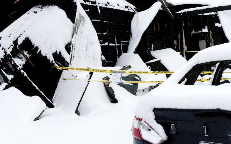 A burned vehicle is seen Thursday beside the charred remains of a garage, where a fire started that destroyed a home last week on China Road in Winslow.