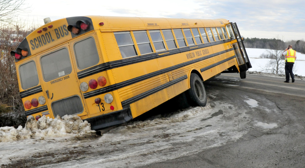 An investigator surveys the scene Thursday after a Winslow school bus ended up in a ditch and became stuck at the corner of Danielle and Benton avenues in Benton.