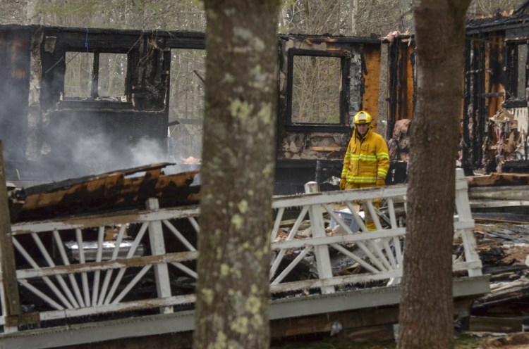 A firefighter walks among the smoldering ashes Jan. 23 at the scene of the fatal fire in the Knox County town of Washington.