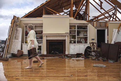 Jenny Bullard carries a pair of boots from her home that was damaged by a tornado Sunday in Adel, Ga.    Branden Camp/Associated Press