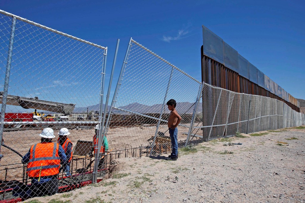 A Mexican boy watches U.S. workers building a section of the U.S.-Mexico border wall at Sunland Park, New Mexico, opposite the Mexican border city of Ciudad Juarez, Sept. 9, 2016. 