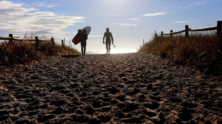 Surfing buddies Stephan Laufer of Germany, left, and Ryan McDermott of Scarborough head toward the water to take advantage of waves at Scarborough Beach State Park. Maine oversees more than 50 state parks and historic sites.