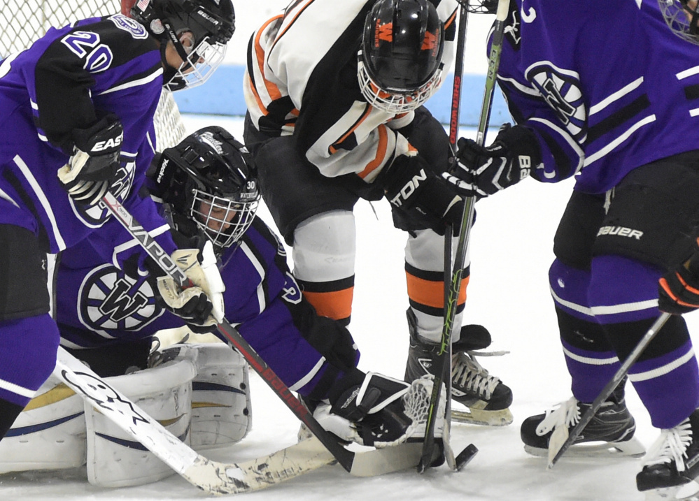 Waterville goalie Nathan Pinnate makes a save on a shot from Winslow forward Tommy Tibbetts (8) as Waterville defensemen Anthony Pinnette, left, and Matt Jolicoeur close in during a Class B North game Feb. 1 at Colby College.