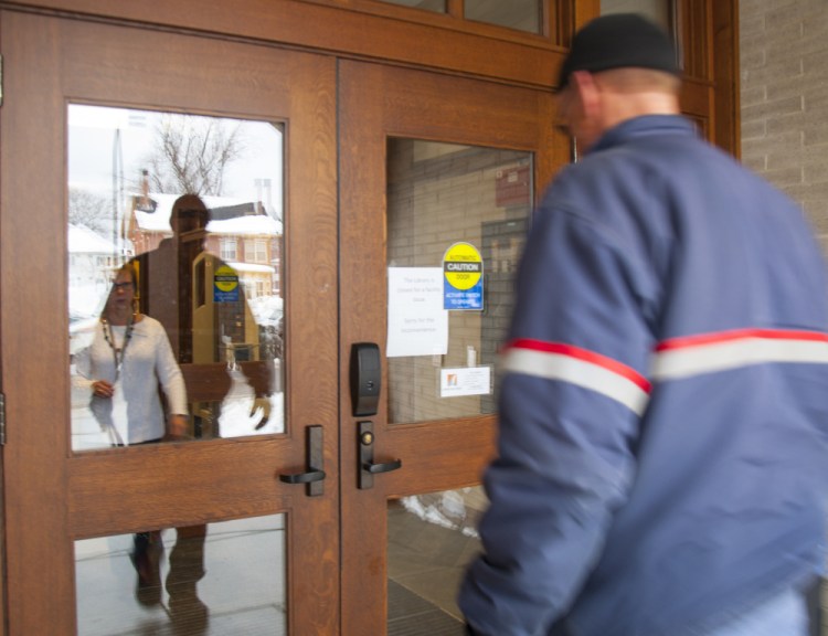 Betsy Pohl, Lithgow Public Library's director, greets the mail carrier Wednesday to let him in while the Augusta library is closed.