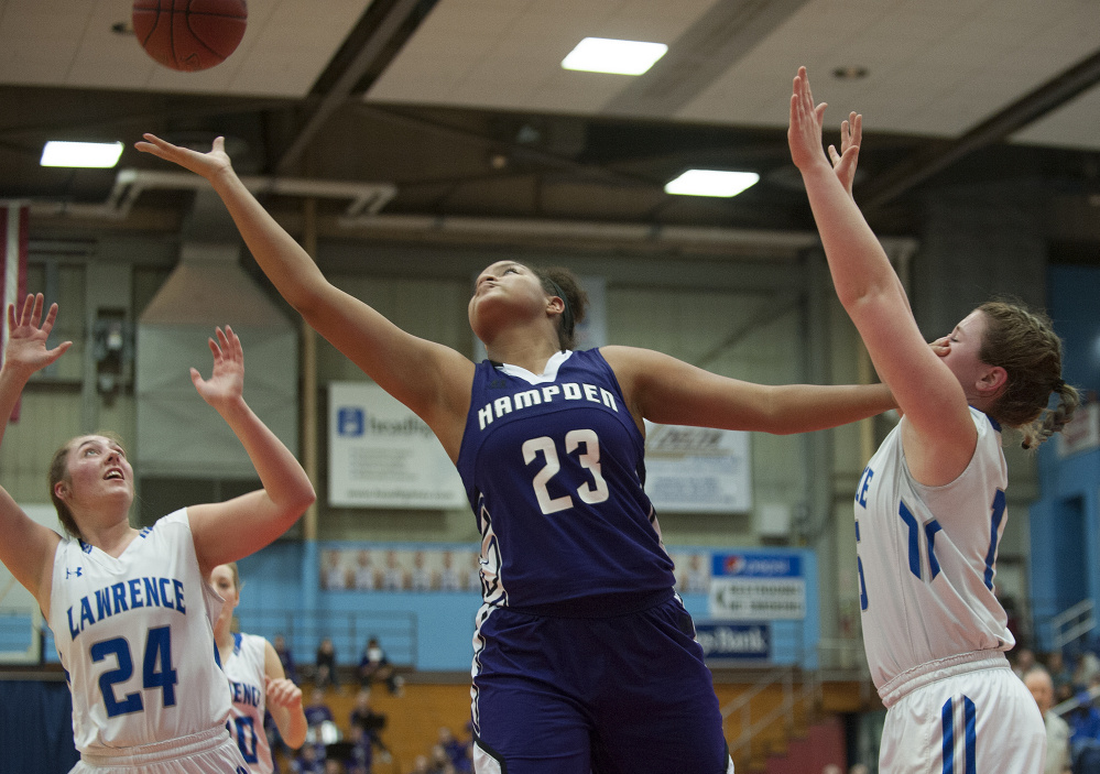 Lawrence's Hunter Mercier, right, takes a hand to the face from Hampden's Bailey Donovan, center, as Molly Folsom looks to grab a rebound during a Class A North quarterfinal game Friday night at the Augusta Civic Center.