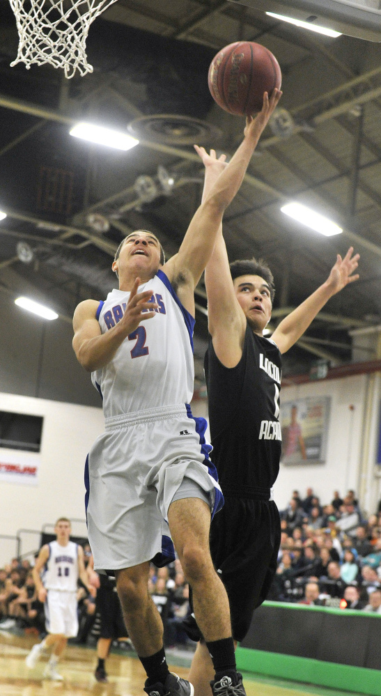 Oak Hill guard Evan Boston goes up for a layup as Lincoln Academy's Keedan Leemen defends during a Class B South quarterfinal game Saturday afternoon at the Portland Expo.