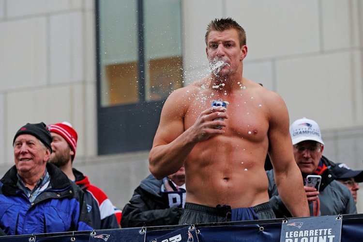 New England Patriots tight end Rob Gronkowski drinks a beer thrown to him from the crowd during the Patriots victory parade through the streets of Boston Tuesday. 