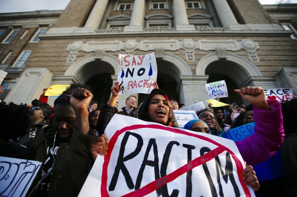 Portland High School senior Awo Ahmed, center, joins with fellow students on the school steps Friday afternoon during a protest in response to an alleged hate crime directed at a group of Casco Bay High School students who were waiting for a bus.