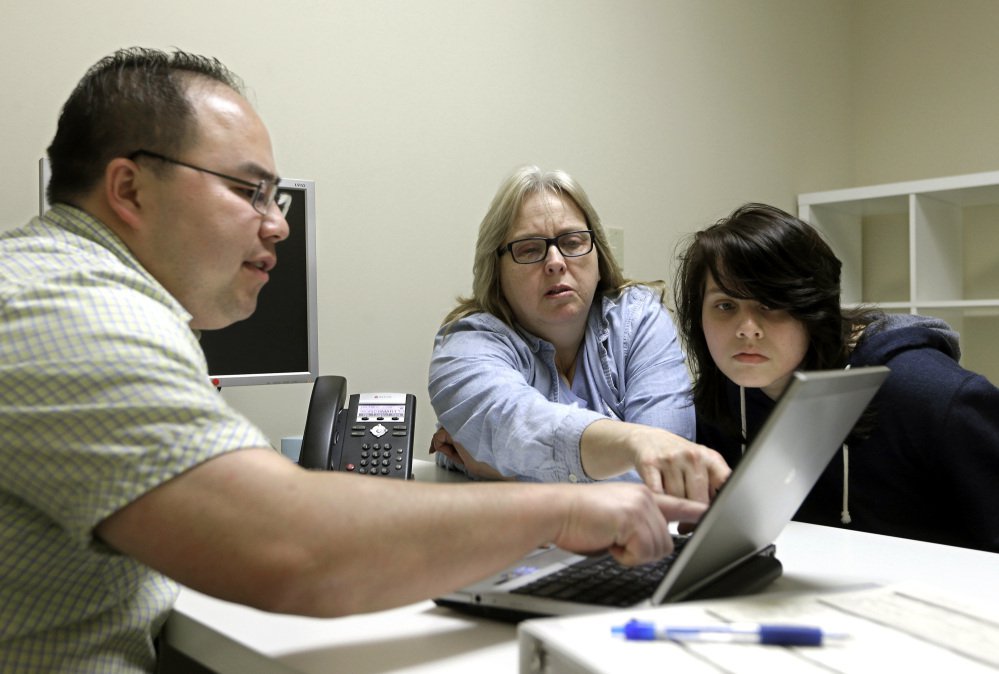 In this Feb. 12, 2015, file photo, enrollment counselor Vue Yang, left, goes over some of the plans available through the state health insurance exchange with Laura San Nicolas, center, accompanied by her daughter, Geena, while enrolling for health insurance at Sacramento Covered in Sacramento, Calif.