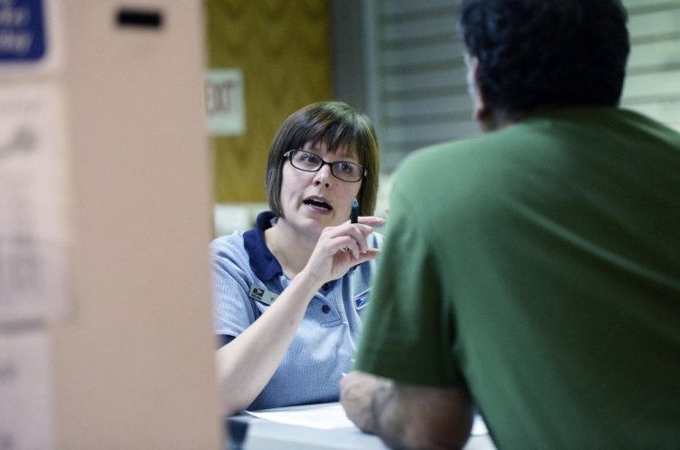 Kara Stevens, a passport clerk at the Portland post office, answers a customer's questions Thursday. Some passport offices are seeing a spike in interest as concern grows about the state's lack of compliance with the federal Real ID law.