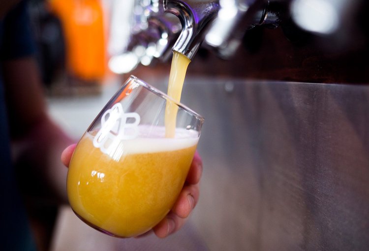 Alex Lascars pours a beer for a customer at the Bissell Brothers Brewing Company's tap room in Portland in August 2016.