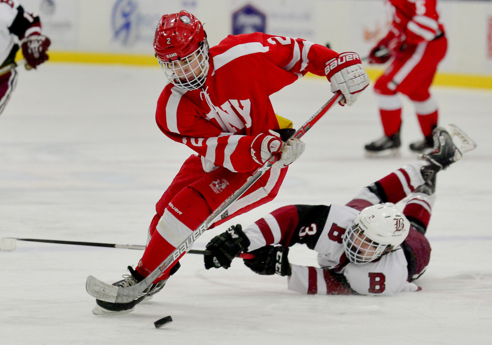 Bangor's Charlie Budd takes a swipe at the feet of Cony's Avery Pomerleau in a fight over the puck in the second period of the Class A North semifinals Saturday in Lewiston.