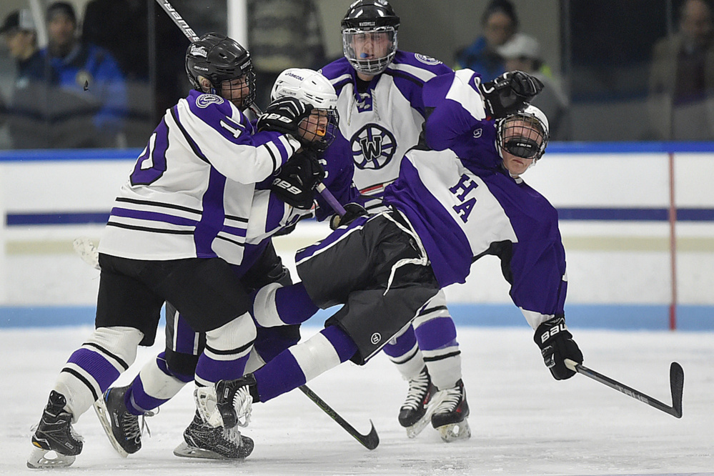 Waterville defenseman Matt Jolicoeur, left, checks Hampden's Mark Thibodeau, center, and Cooper Leland during a Class B North semifinal Saturday night at Alfond Rink in Waterville.