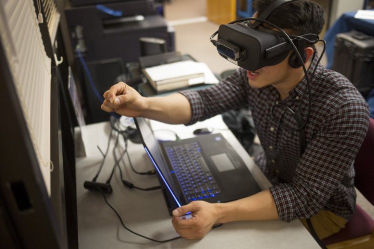 Ryan Hoang, a first-year medical student at UNE, experiences how just grasping a pencil can be challenging when you're suffering from macular degeneration, courtesy of virtual reality software. "It lets you experience the reality of having no control," Hoang said.