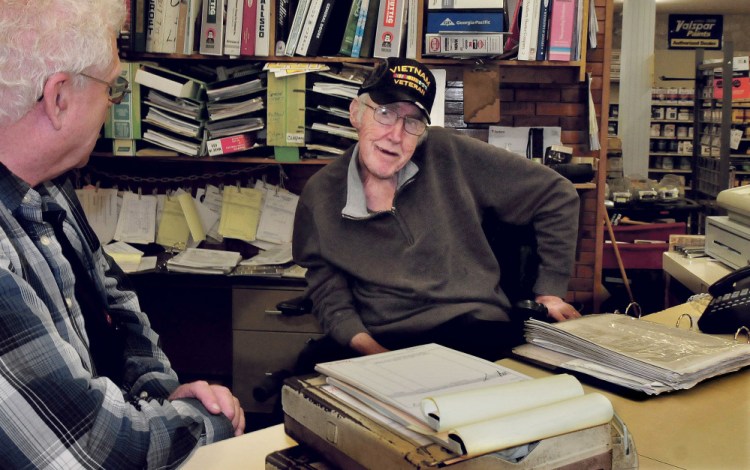 Lakeview Lumber company co-owner Carl Farris, right, spends seven days a week behind the counter helping customers at the store in China. Farris, who has multiple sclerosis, speaks Wednesday with longtime employee Gene Cowing.