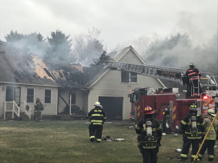 Firefighters work to open the garage roof as they battle a fire Wednesday afternoon on Hurley Drive in Richmond.