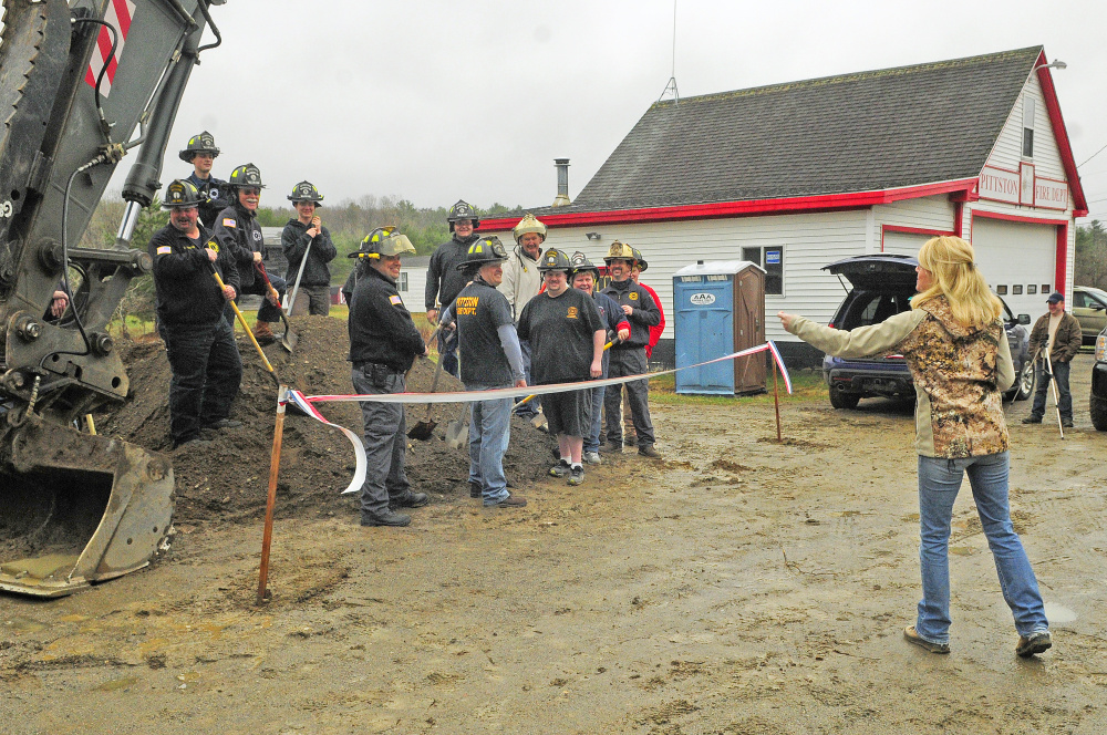 Kerri Malinowski, right, arranges shovel-carrying Pittston firefighters onto a dirt pile for a photo during a ceremonial groundbreaking for the new fire station Saturday in East Pittston. Construction has already begun on the new station that will replace an old one seen in background.