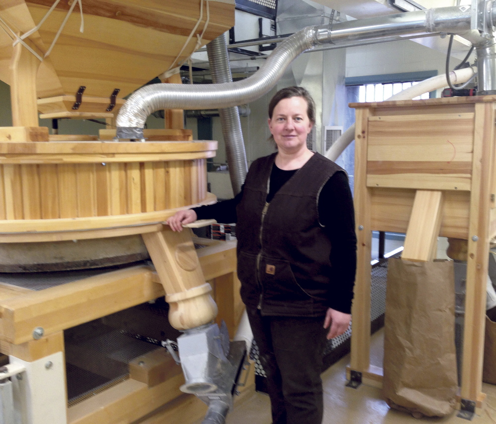 Amber Lambke stands beside a working mill grinding flour April 30, 2014, at the Somerset Grist Mill in Skowhegan. Lambke, president of Maine Grains, is the first speaker in Thomas College's series on entrepreneurship and innovation.