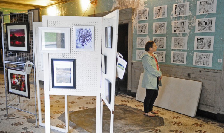 Maureen Booth looks at art on display May 13, 2016, in the Colonial Theatre lobby during the Raw Space Augusta Art Walk in downtown Augusta.
