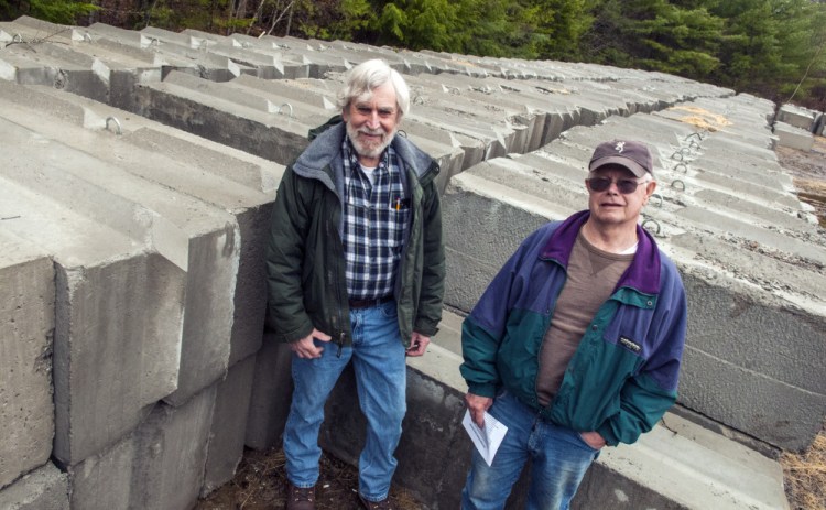 President Scott Farnum, left, and Treasurer Paul Okerholm pose for a portrait Thursday with hundreds of cement blocks that will form the new side walls at the West Gardiner Rod & Gun Club gun range behind the clubhouse.